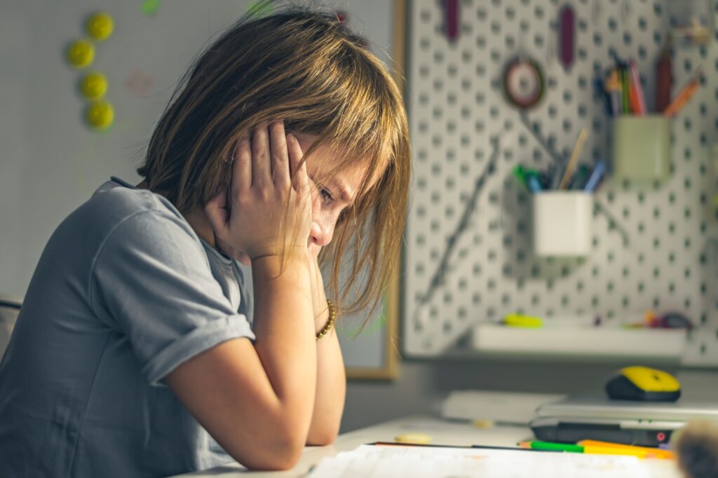 upset schoolgirl doing lessons, her homework. learning difficulties