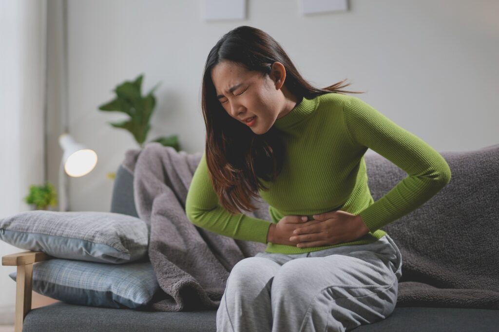 Young woman experiencing stomach pain at home